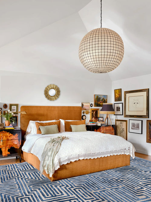 Warm eclectic bedroom design with gallery wall, Kevin Francis Design Knossos hand-tufted navy maze rug, capiz shell chandelier