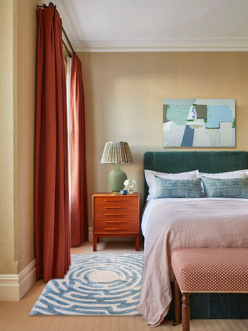London bedroom design with grasscloth wallpaper, teal velvet bed, mid-century nightstand, Kevin Francis Design Amiens blue tufted maze rug, abstract painting