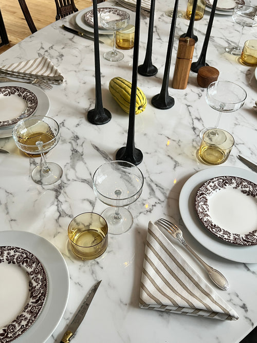 Moody, simple fall table setting with iron candleholders, Spode plates, striped napkins, and yellow glassware by Atlanta designer Kevin Francis Design