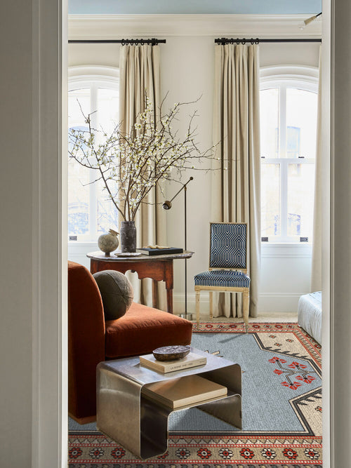 Bedroom sitting area with Kevin Francis Design Selendi hand-knotted wool area rug, red slipper chair, brass side table, New York City interiors