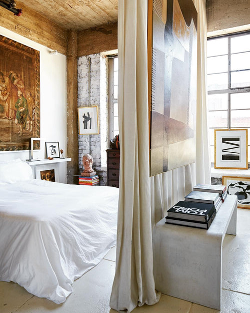 Romantic loft bedroom design with linen curtain wall, steel framed windows, antique tapestry, and concrete floors on Kevin Francis Design