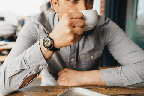 Man drinking coffee while wearing Last Laugh Tattoo watch