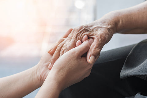 Young hand holding an elderly hand, pain management