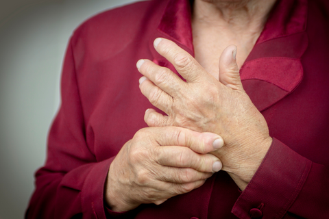 Woman holding her hands in pain with rheumatoid arthritis.