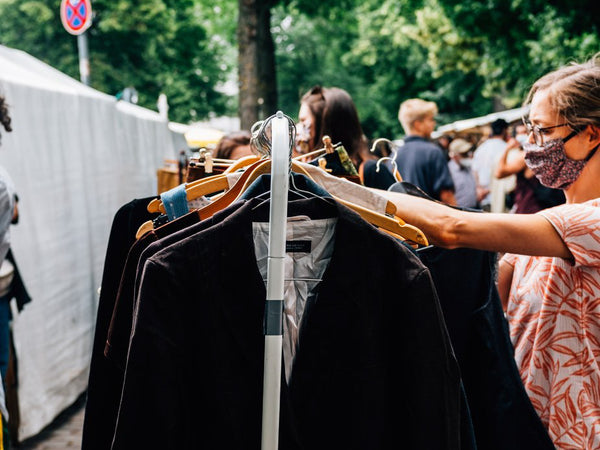 Person shopping for clothing at an outdoor market.