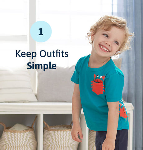 Smiling blonde toddler boy in blue outfit with overlayed text "keep outfits simple" on image