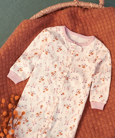 Floral footed pajama placed in a baby moses basket ontop of an orange blanket