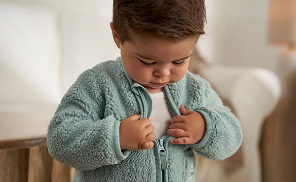 With a determined look, a little boy skillfully adjusts his snug fleece jacket, getting ready for a chilly adventure.