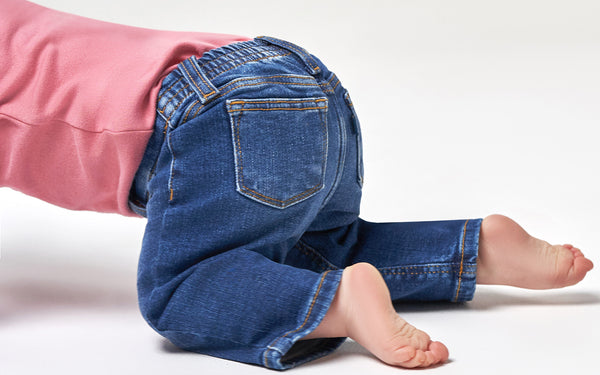 Baby wearing blue jeans and pink shirt crawling out of the camera shot