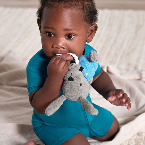 Dark haired baby boy wearing deep aqua blue outfit playing with teething toy