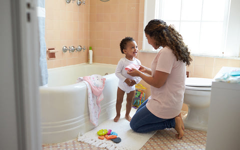 Mother and toddler in bathroom getting ready for a bath.