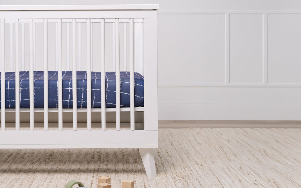 white baby crib with blue sheets