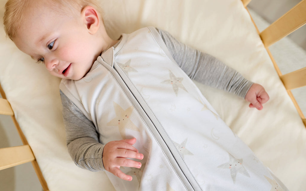 baby boy in crib wearing celestial pattern sleep bag
