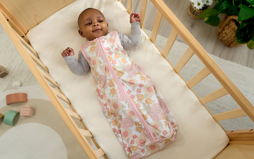baby girl in crib wearing floral pattern sleep bag