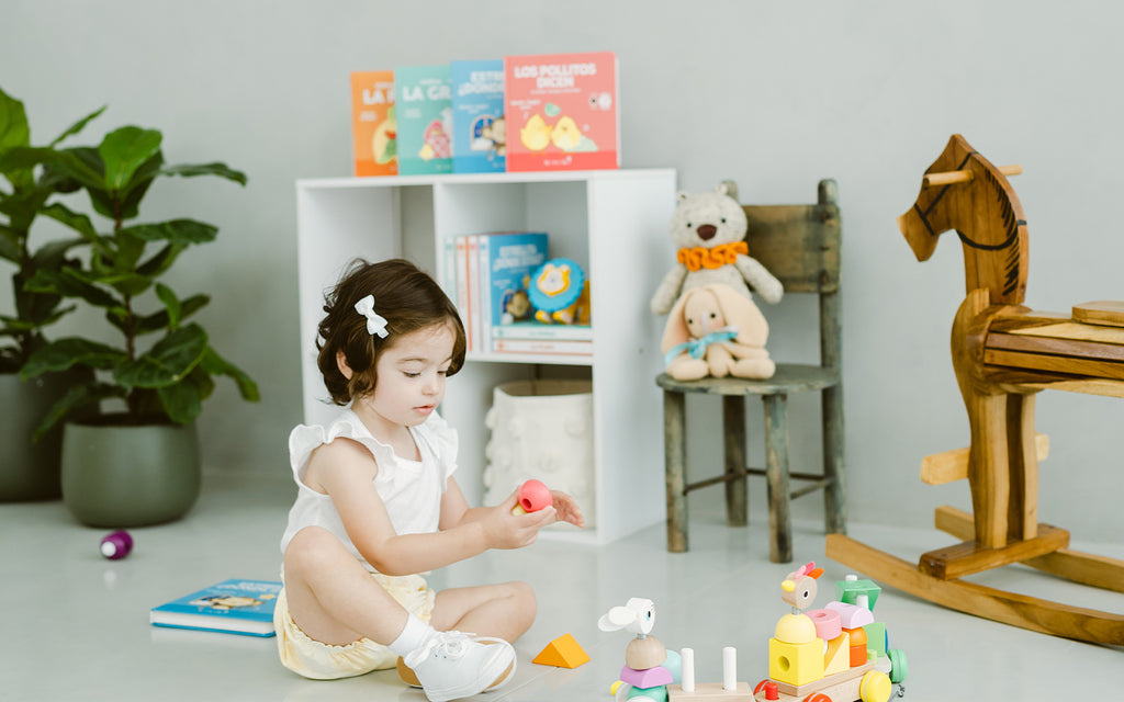 toddler girl sitting in nursery playing with toys