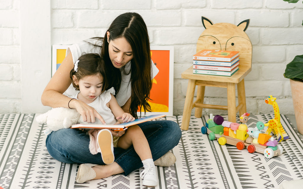 child sits on mother's lap as they read a book together