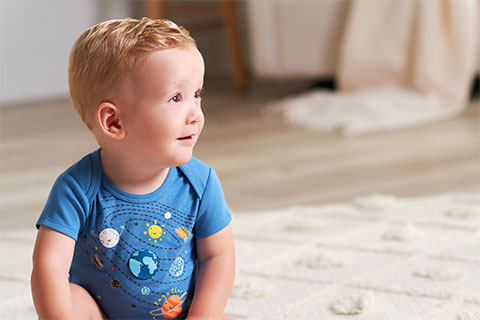 Baby boy smiling with profile towards camera