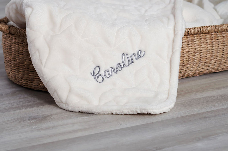 Plush blanket in wicker basket embroidered with name "Caroline"