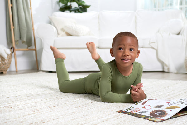 Toddler boy reading a book wearing green pajama set