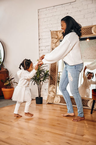 mother and daughter dance together in front of a mirror
