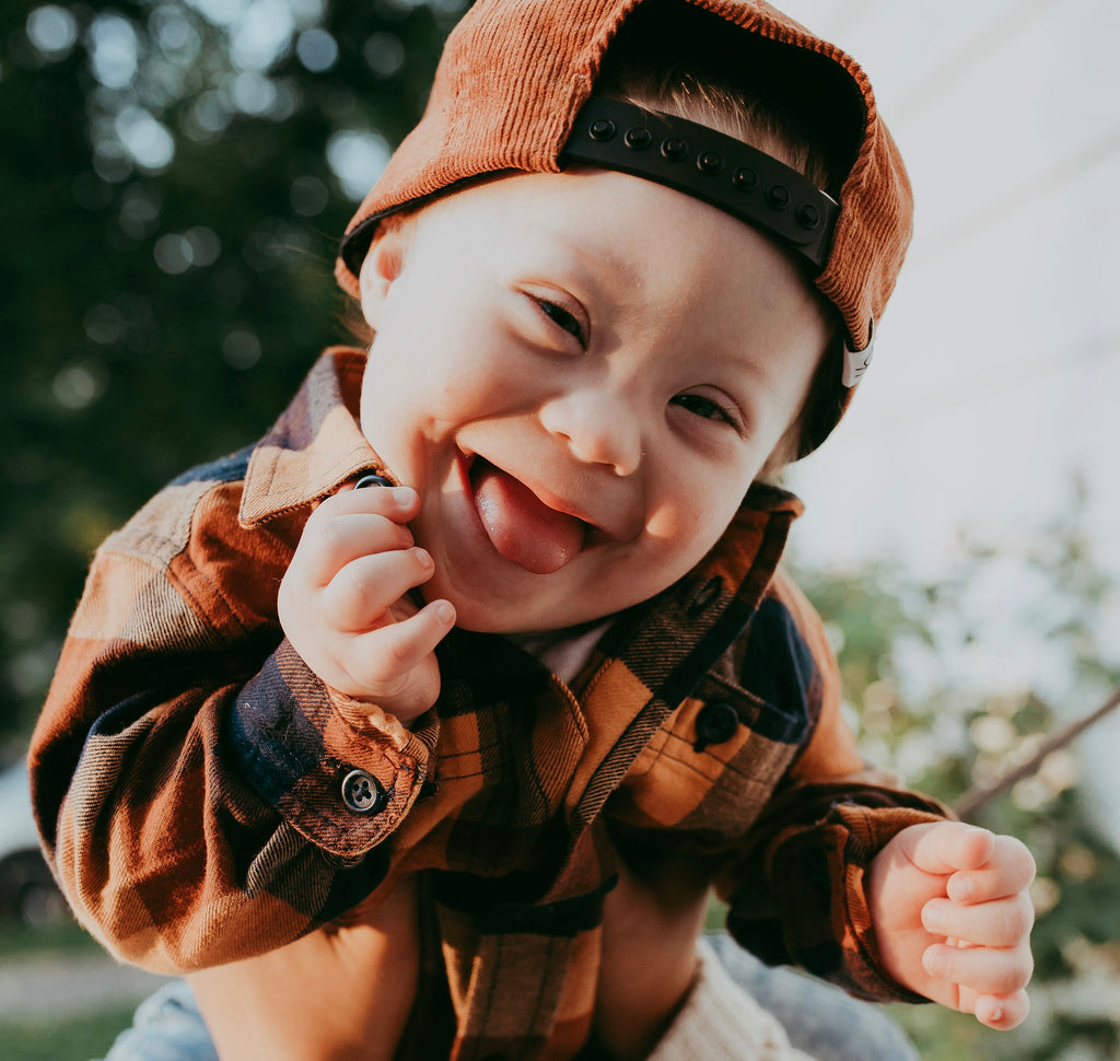 close up on child in flannel shirt and hat smiling widely