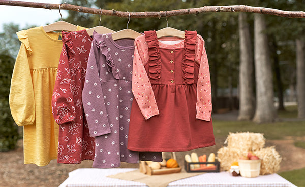 toddler girl dresses hanging from branch with pumpkins beneath