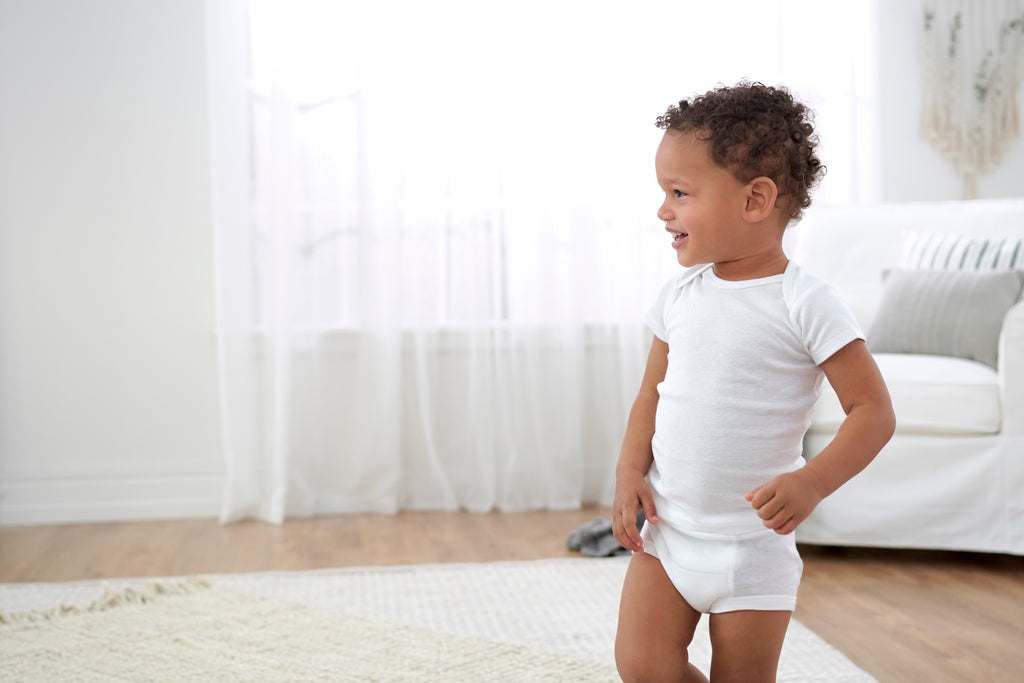 Little boy in white t-shirt standing in the middle of a white room.