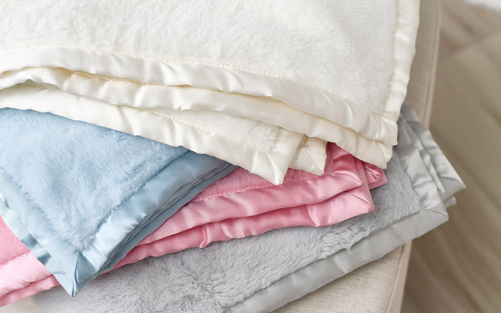 A lavish heap of blankets in opulent shades of pink, blue, and white, exuding an aura of comfort and tranquility.