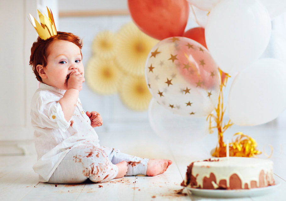 Redhaired, messy baby boy tasting and eating cake