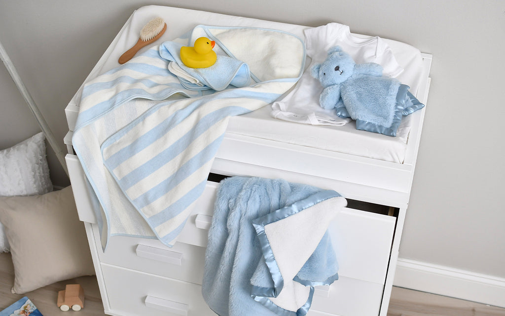 A lavish baby changing table, draped in a sophisticated blue and white striped towel, evoking a sense of refinement and tranquility.
