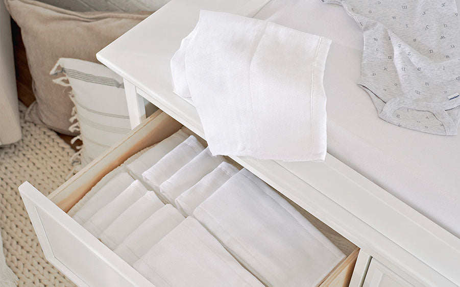Essential white diaper cloths gently placed within a nursery drawer.