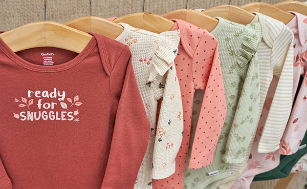 Get ready for cozy cuddles! Fall-themed baby clothes, including adorable bodysuits, are showcased on a rack with print that says "Ready for Snuggles".