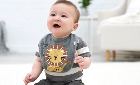 Baby boy sitting on floor in a grey striped lion motif outfit