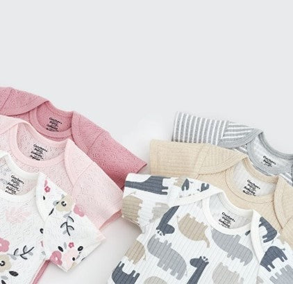Six baby Onesies® bodysuits with various patterns lying on a gray background.