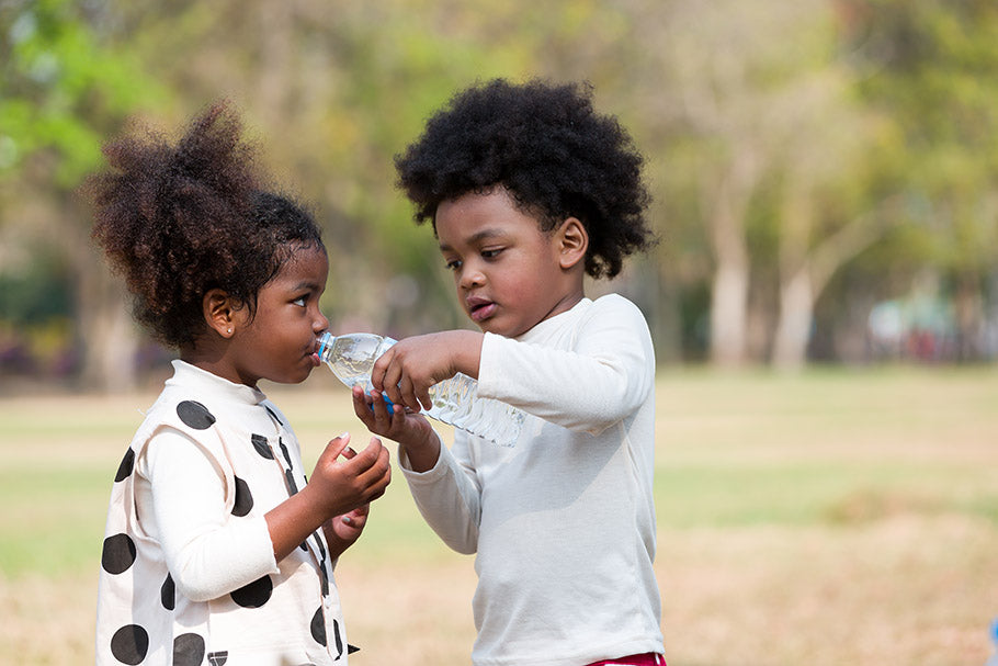 children drinking water while playing in the park