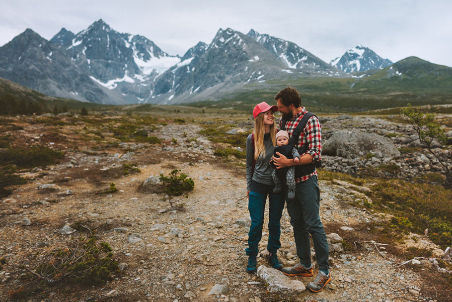 A picturesque scene unfolds as a couple stands amidst the majestic Alaska mountains, embracing the serenity of nature's grandeur.