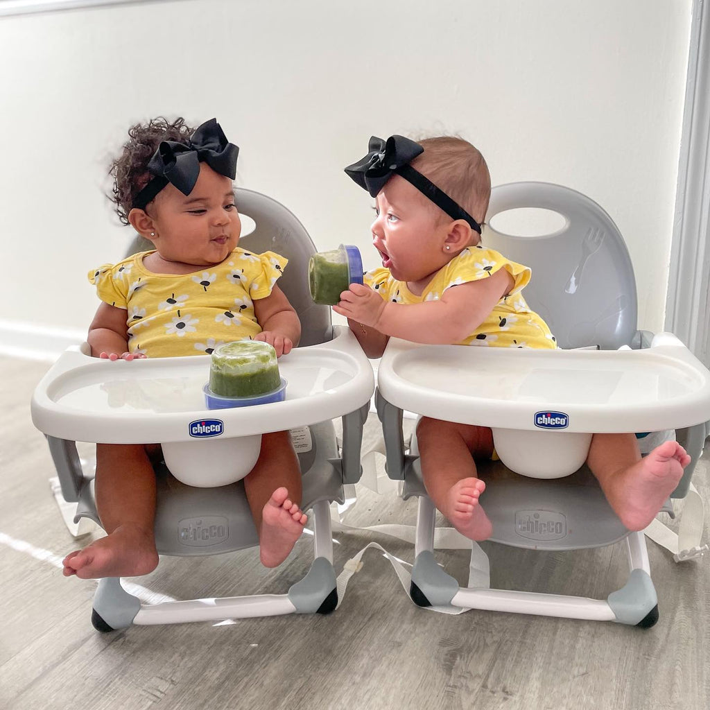 Two twin girls eating together in yellow matching outfits