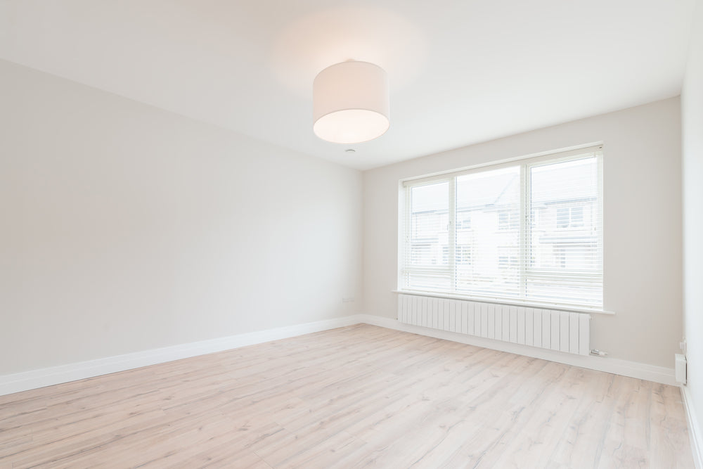 empty small bedroom with tan walls and wood floors