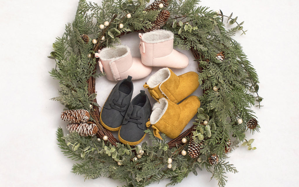 A lavish wreath adorned with dainty baby shoes and delicate pine cones, exuding an air of elegance and charm.