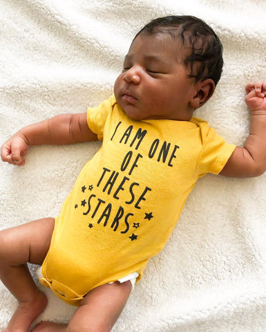 baby sleeping in yellow bodysuit