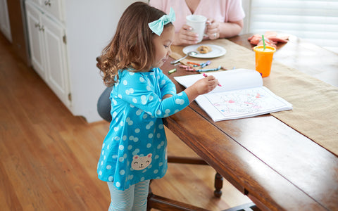 toddler girl standing at kitchen table with children's book