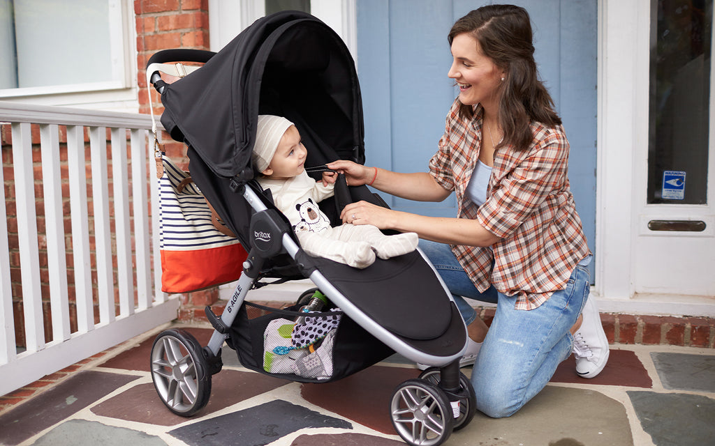 A caring woman assists a baby in a stroller, ensuring their safety and comfort.