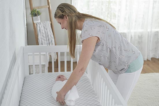 mom tending to baby in crib
