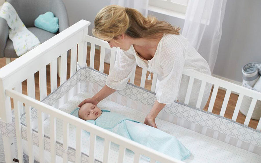 mother putting baby in cradle