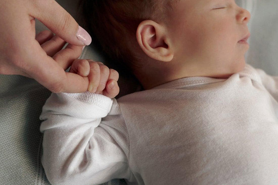 sleeping child holds mothers finger