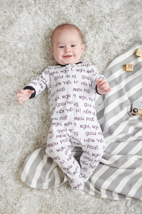 smiling baby in pajamas laying on blanket