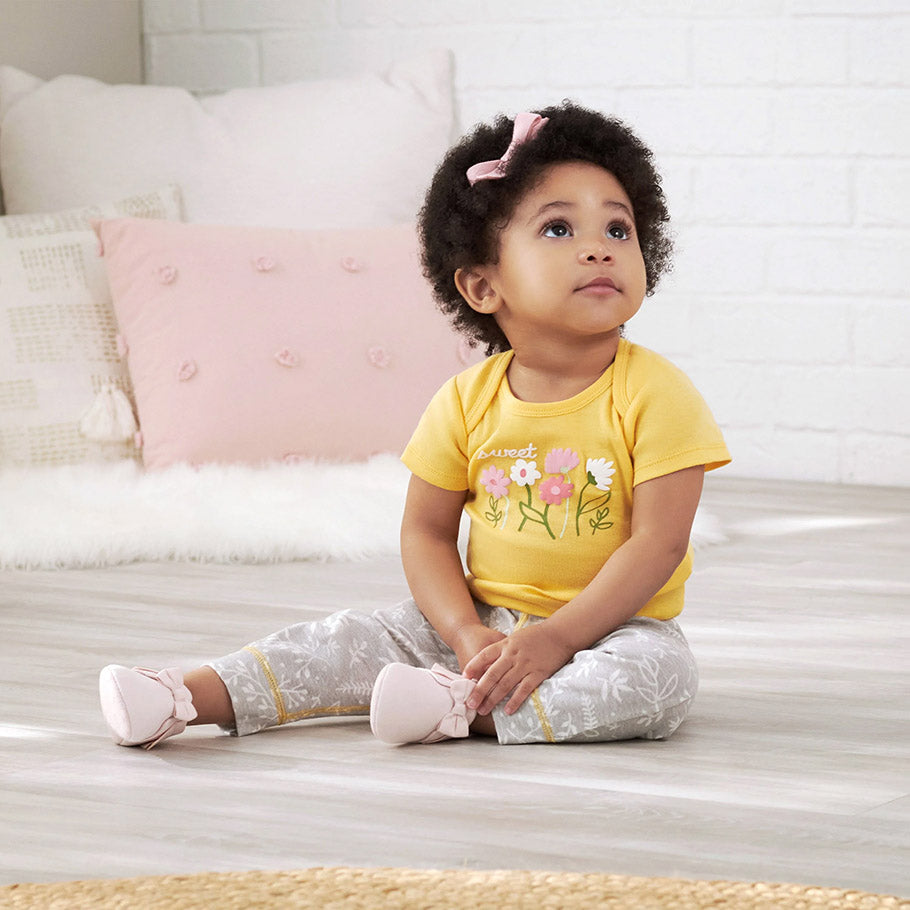 A cute baby girl in a yellow shirt and pink shoes, ready to conquer the world with her adorable style!
