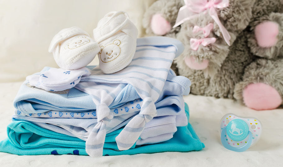 A delightful sight of baby clothes neatly piled up, with a cuddly stuffed elephant adding an extra touch of cuteness to the scene.