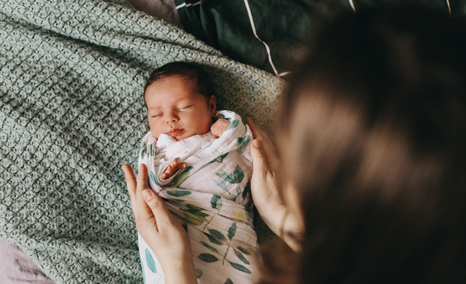 Mother holding a swaddling newborn baby in a blanket