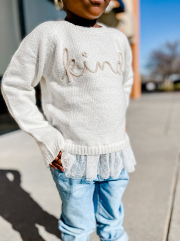 Ryann with her hands on her hips showcasing her white sweater